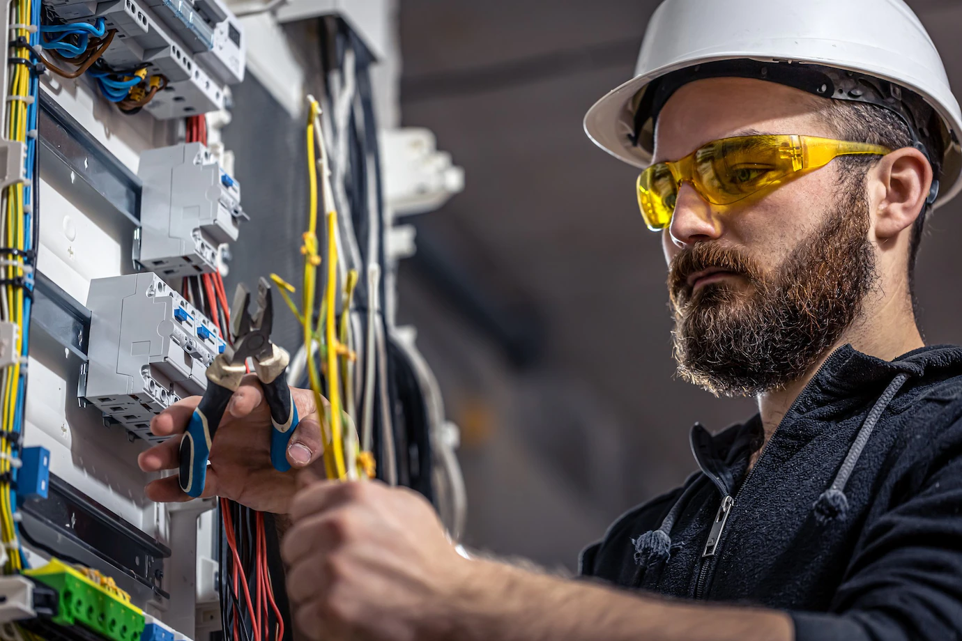 male-electrician-works-switchboard-with-electrical-connecting-cable_169016-15204